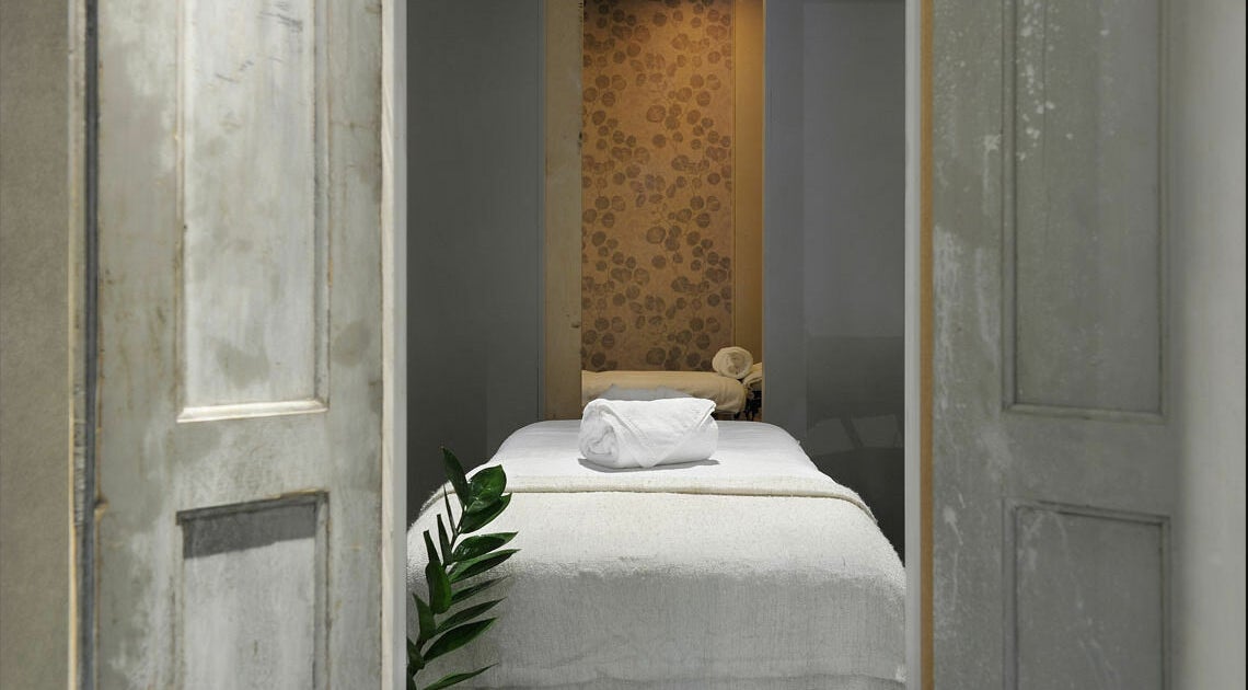 Knusse behandelkamer bij Spa Manda, Haarlem, Noord-Holland, NL, met rustieke deuren en zachte handdoeken.