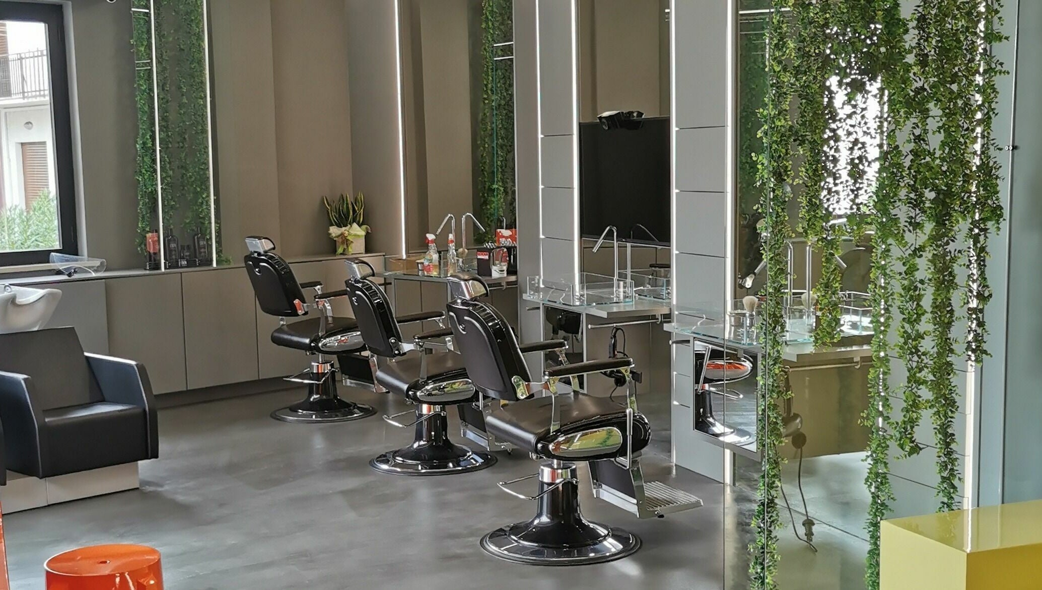 Interno moderno di Modo Central Barbieria a Porto Sant'Elpidio, Marche, con sedie e decorazione verde.