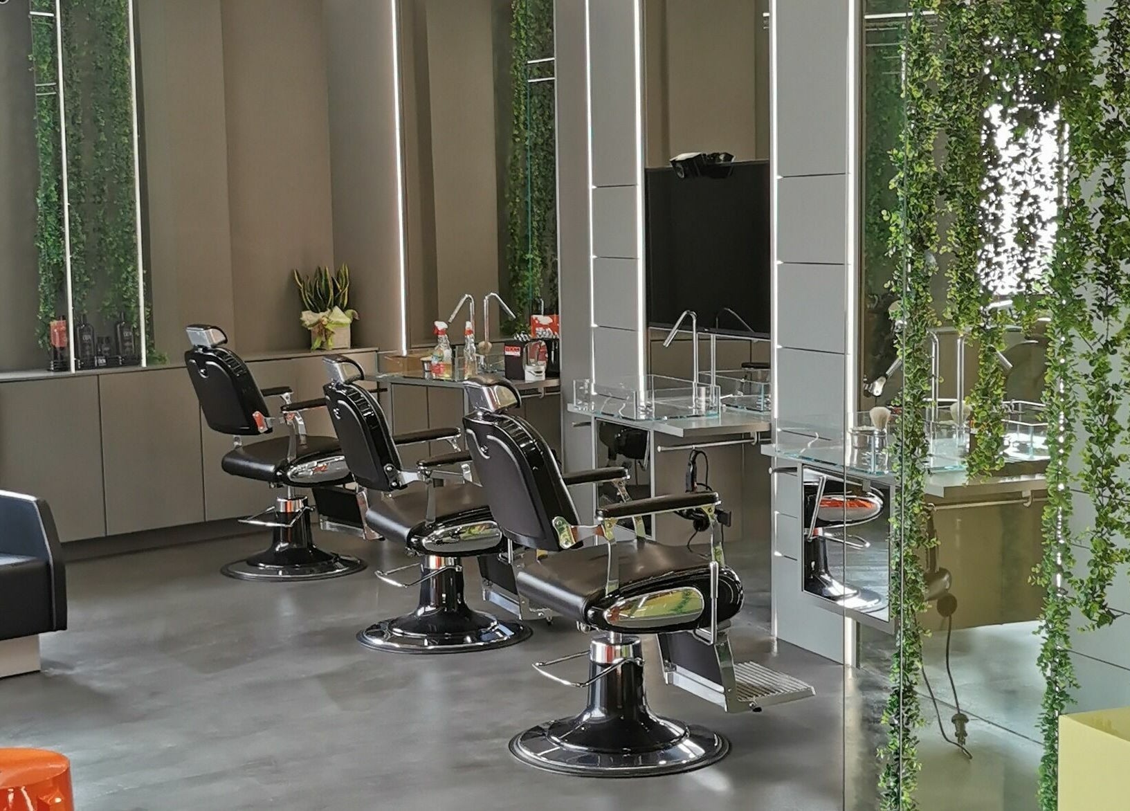 Interno moderno di Modo Central Barbieria a Porto Sant'Elpidio, Marche, con sedie e decorazione verde.