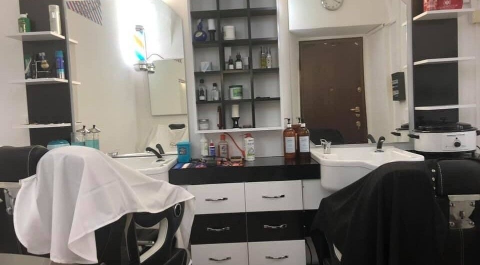 Interno del 3K Barber Shop a Locarno, Ticino, CH, con sedie da barbiere e prodotti per capelli.