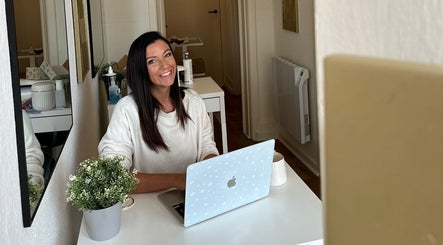 Smiling woman at desk in The Beauty Room, Bournemouth, England, GB, creating a welcoming salon atmosphere.