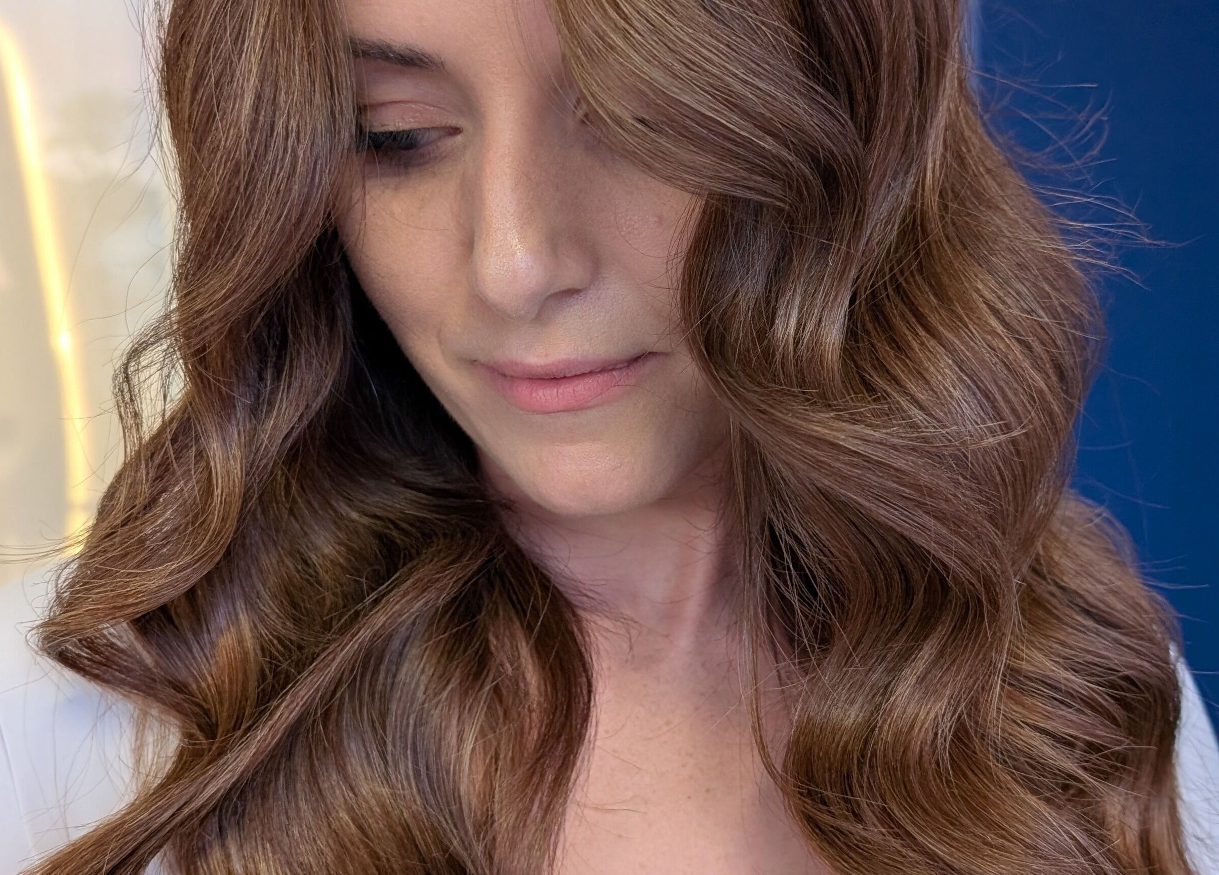 Woman with glossy waves at Colorbox Hair, Coomera, QLD, AU, showcasing soft curls in brunette hair.