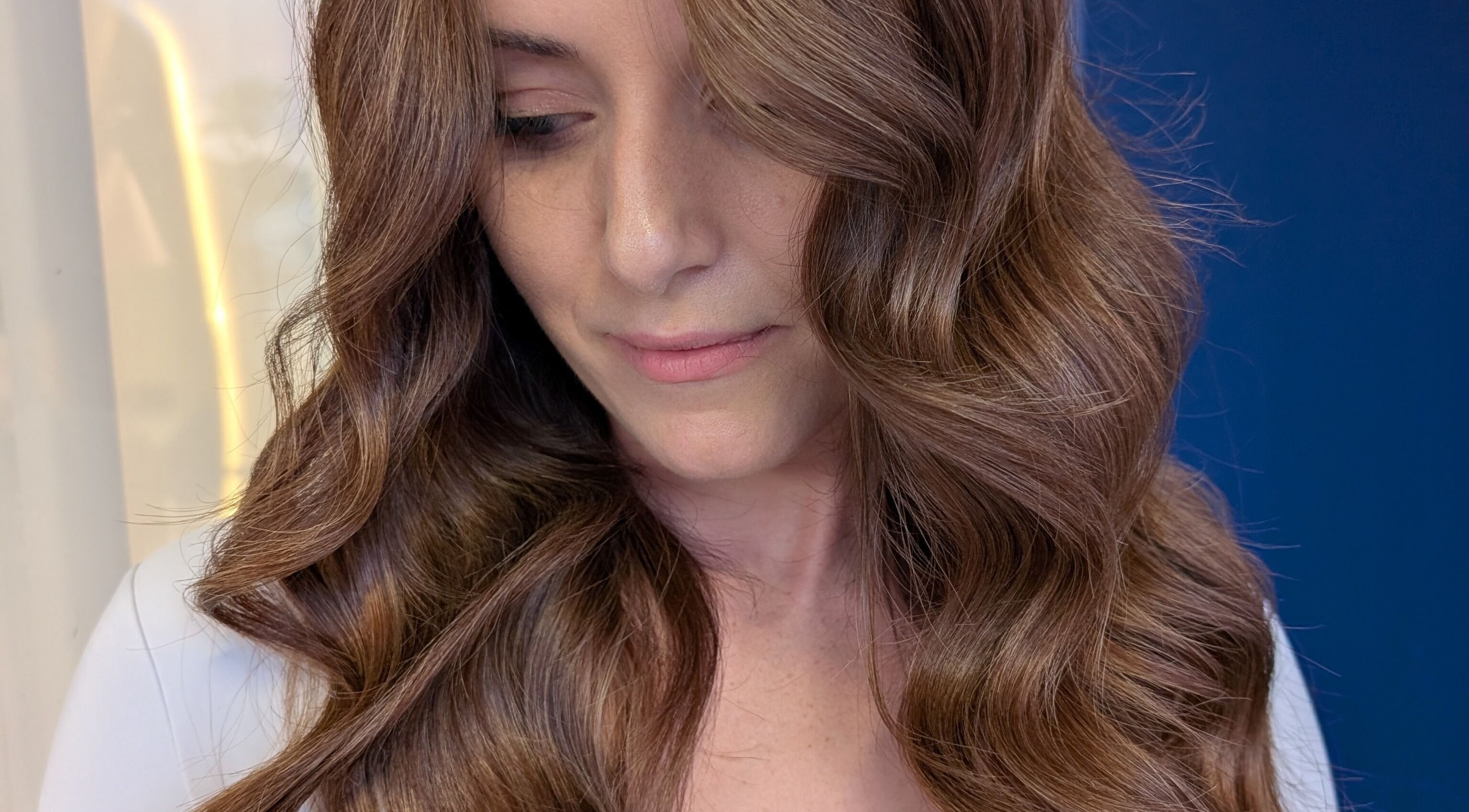 Woman with glossy waves at Colorbox Hair, Coomera, QLD, AU, showcasing soft curls in brunette hair.