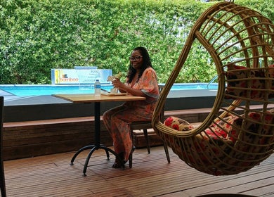 Woman relaxes at The Bamboo Retreat's patio in St. George, BB beside pool amid lush greenery.