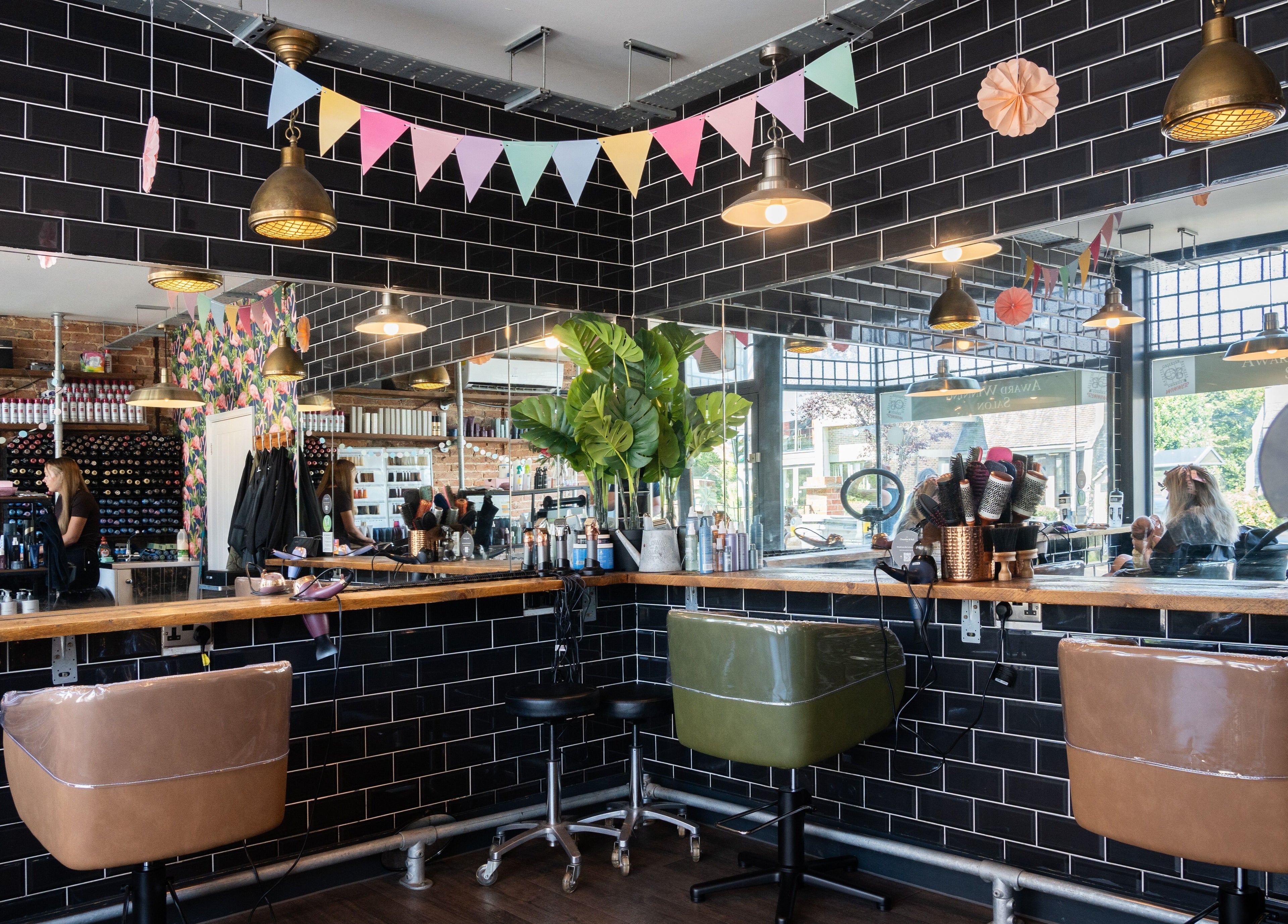 Chandler & Hall salon in Southbourne, England, GB, showcasing stylish chairs and black tile walls.