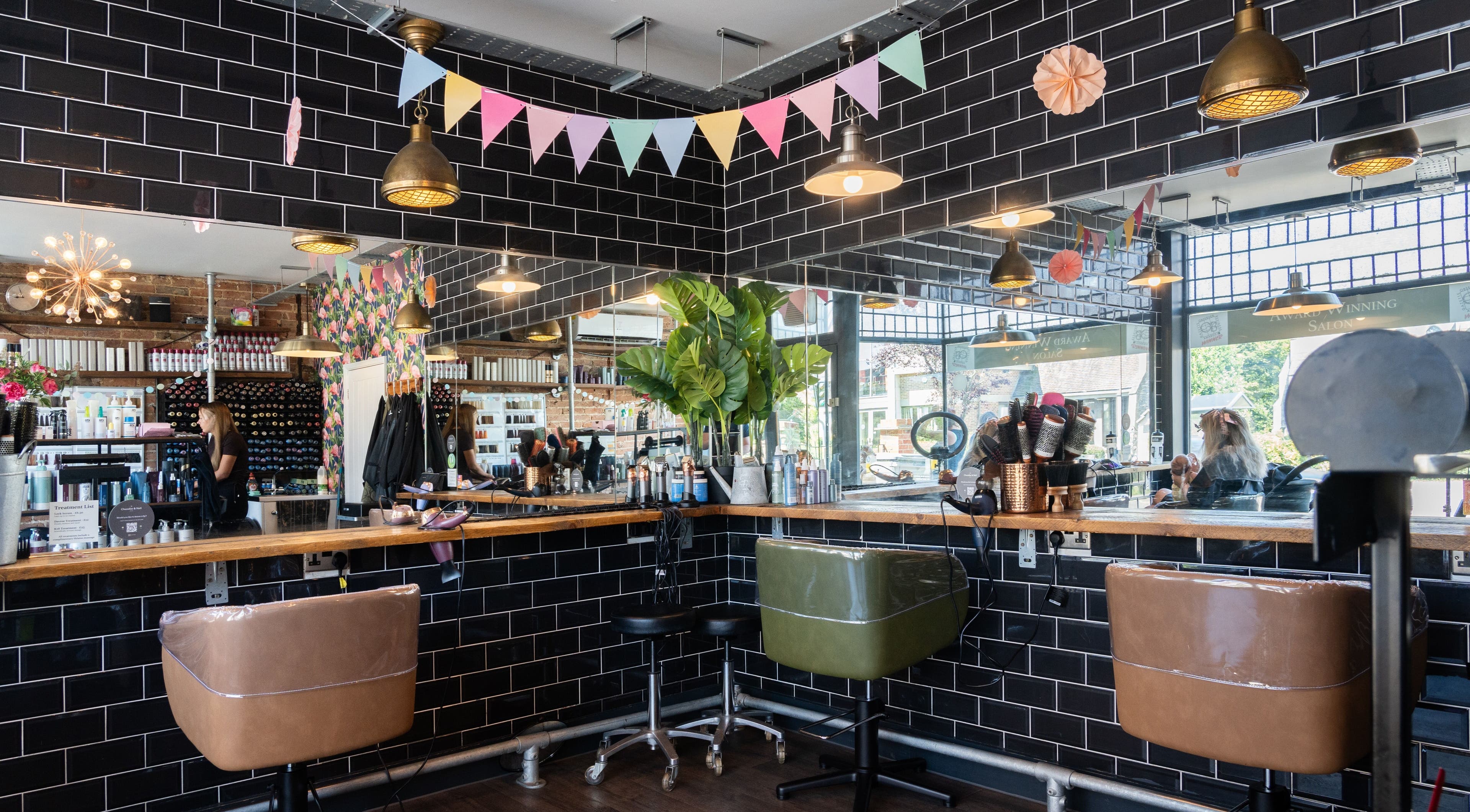 Chandler & Hall salon in Southbourne, England, GB, showcasing stylish chairs and black tile walls.