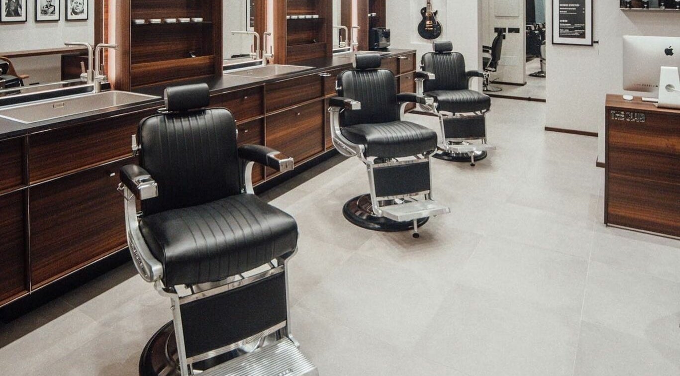 Interno moderno di The Club Barbershop - Adria, Veneto, IT con poltrone eleganti.