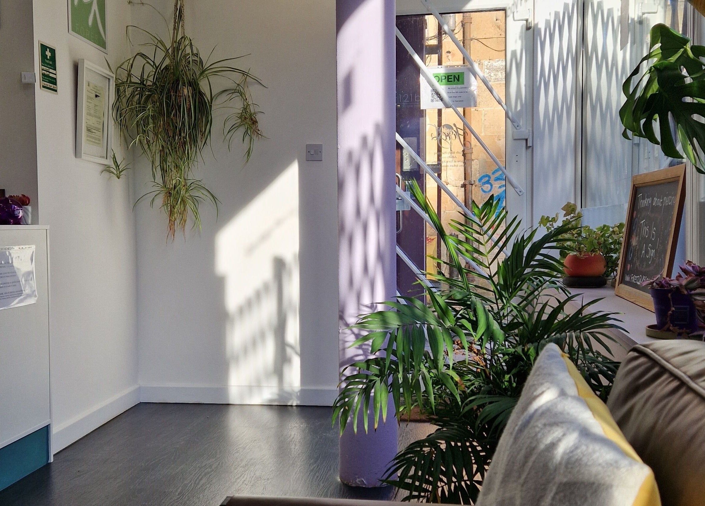 Bright and welcoming entrance of Forest Piercing in Glasgow, Scotland, GB with plants and cozy seating.