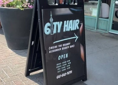 Street sign for 6ity Hair salon in Whitby, Ontario, CA displaying hours and location details.