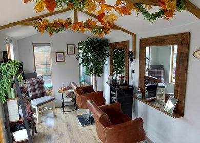 Chic interior of The Hair Lodge in Wakefield, England, GB showcasing rustic charm with leather chairs and plant decor.