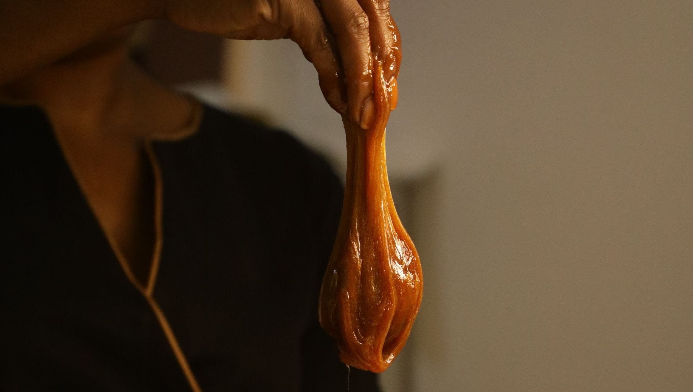 Hand holding caramel sugar paste at HALAWA PRIS LAGOS POP-UP in Lekki, Lagos, NG. Perfect for waxing services.