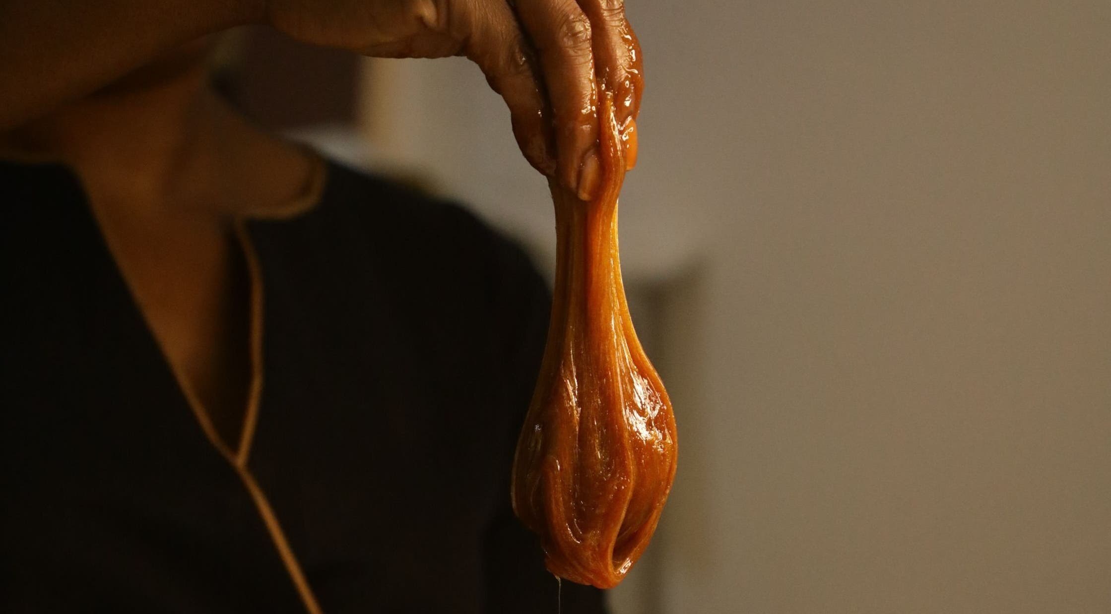 Hand holding caramel sugar paste at HALAWA PRIS LAGOS POP-UP in Lekki, Lagos, NG. Perfect for waxing services.