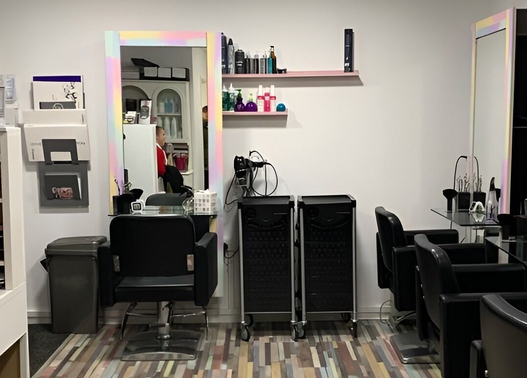 Modern salon interior at Colour Chic in Redruth, England, GB with black chairs and colorful decor.