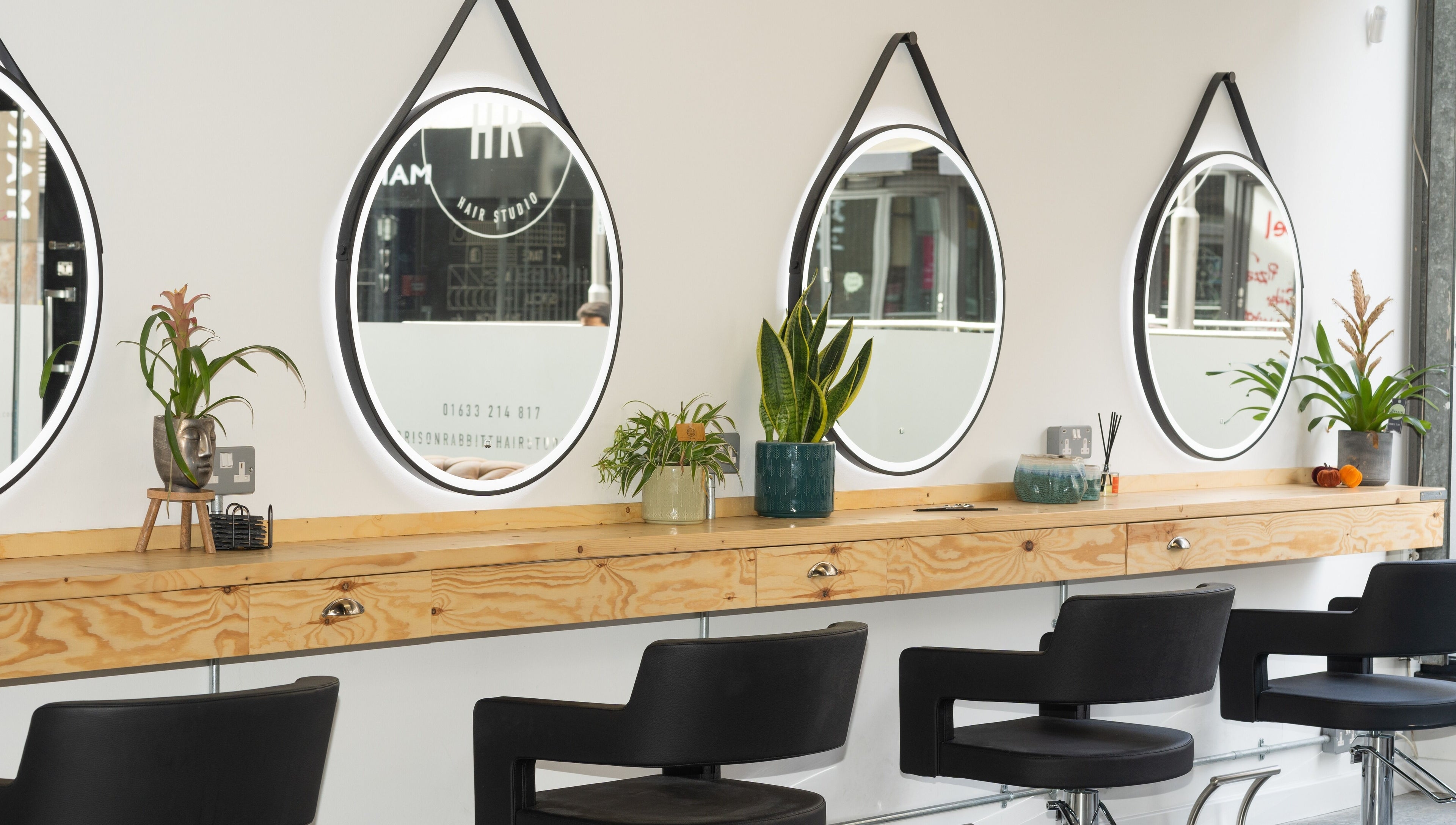 Stylish salon interior with mirrors and plants at Harrison Rabbitt Hair Studio in Newport, Wales, GB.
