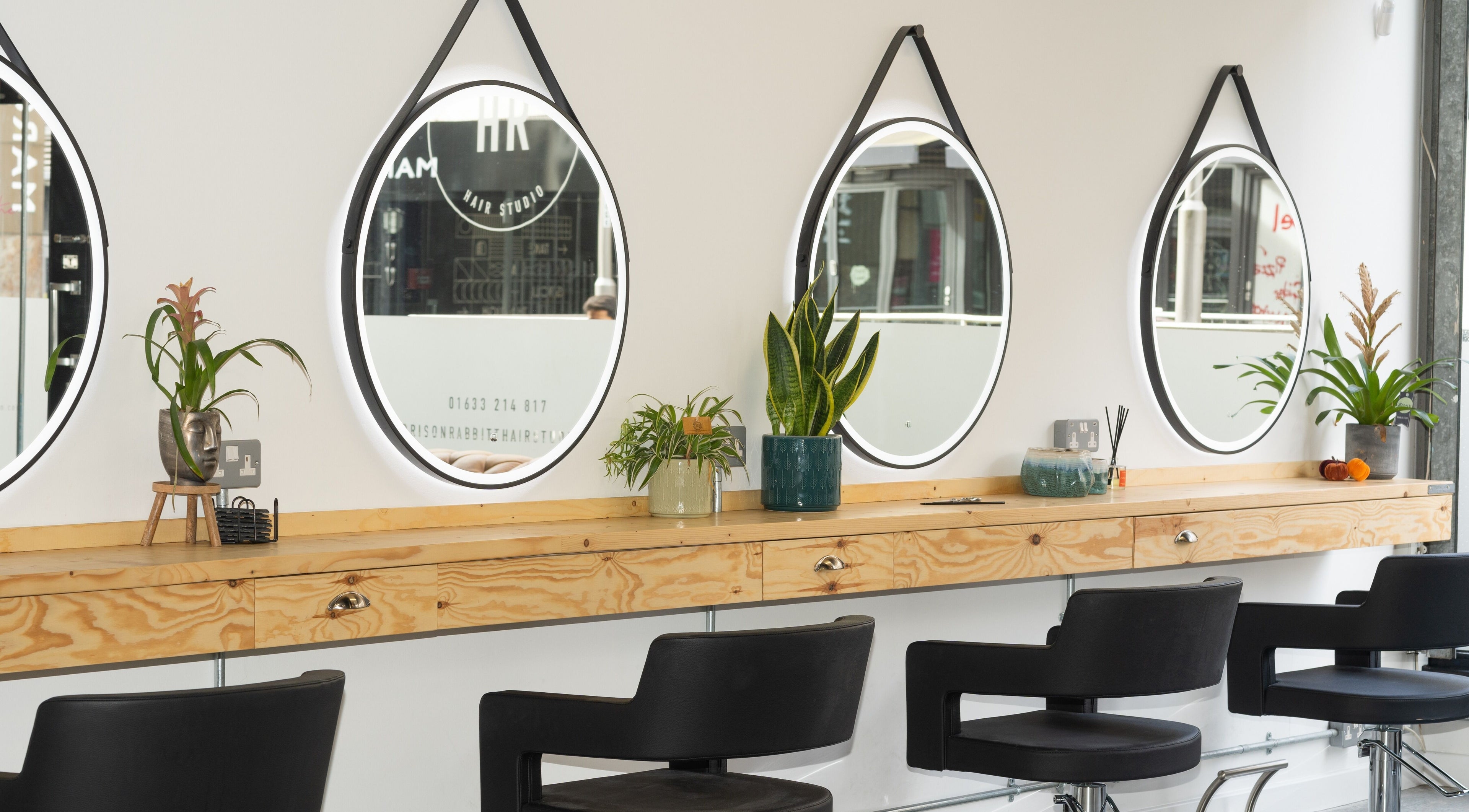Stylish salon interior with mirrors and plants at Harrison Rabbitt Hair Studio in Newport, Wales, GB.