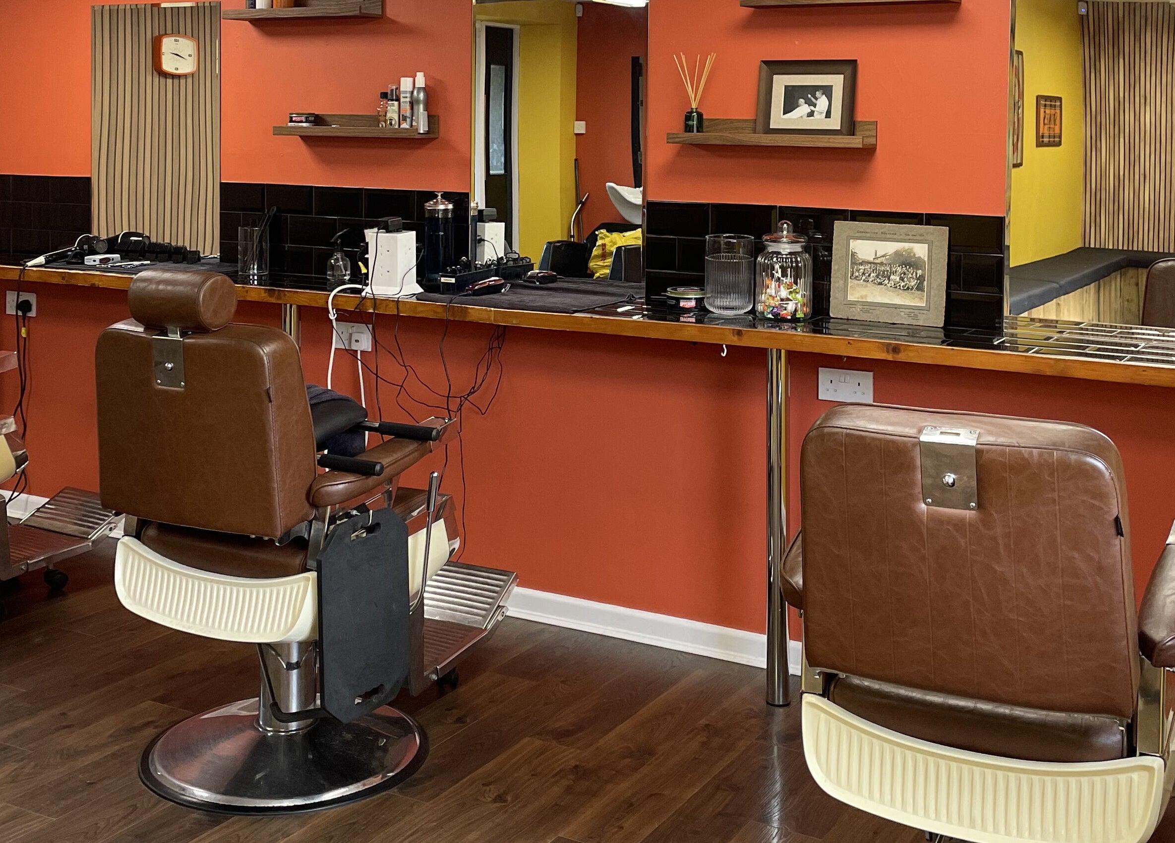 Interior of Wild's Barbershop in Sheffield, England, GB with vintage barber chairs and orange walls.