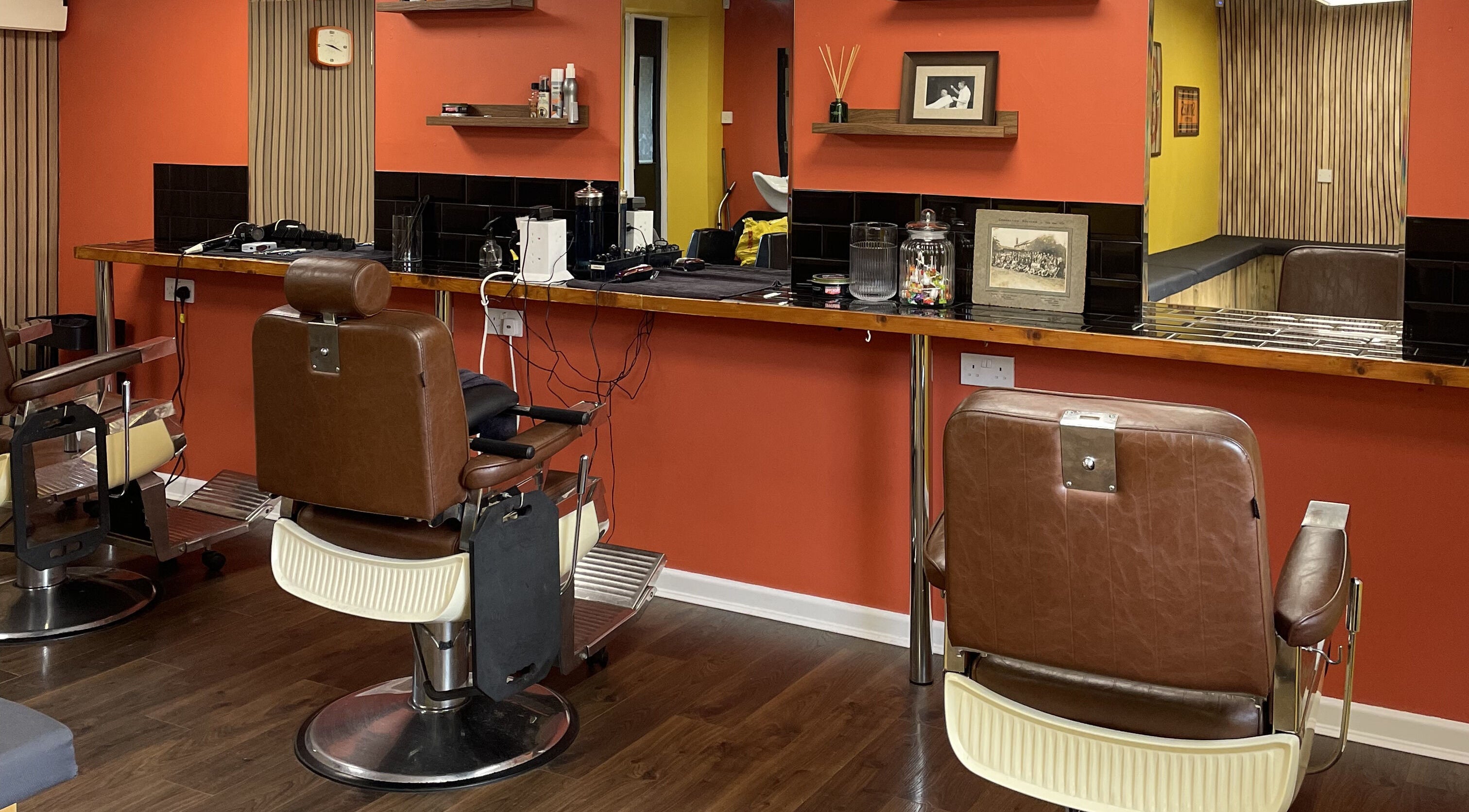 Interior of Wild's Barbershop in Sheffield, England, GB with vintage barber chairs and orange walls.
