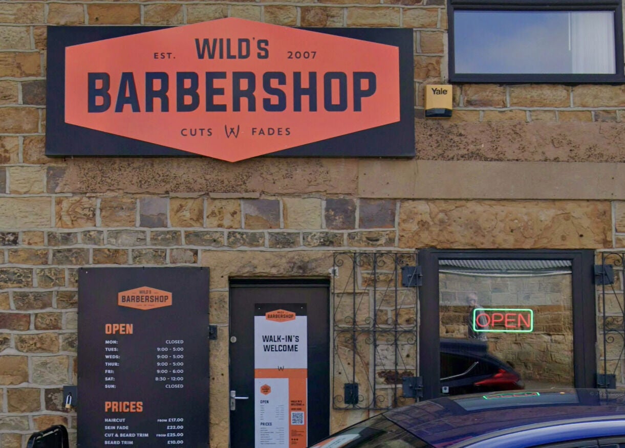 Front view of Wild's Barbershop in Sheffield, England, GB with its sign and open hours display.