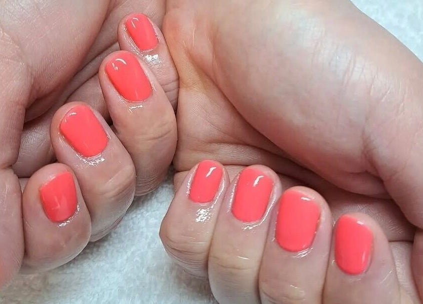 Close-up of coral manicured nails at Room 2, Abergavenny, Wales, GB; showcasing expert nail care.