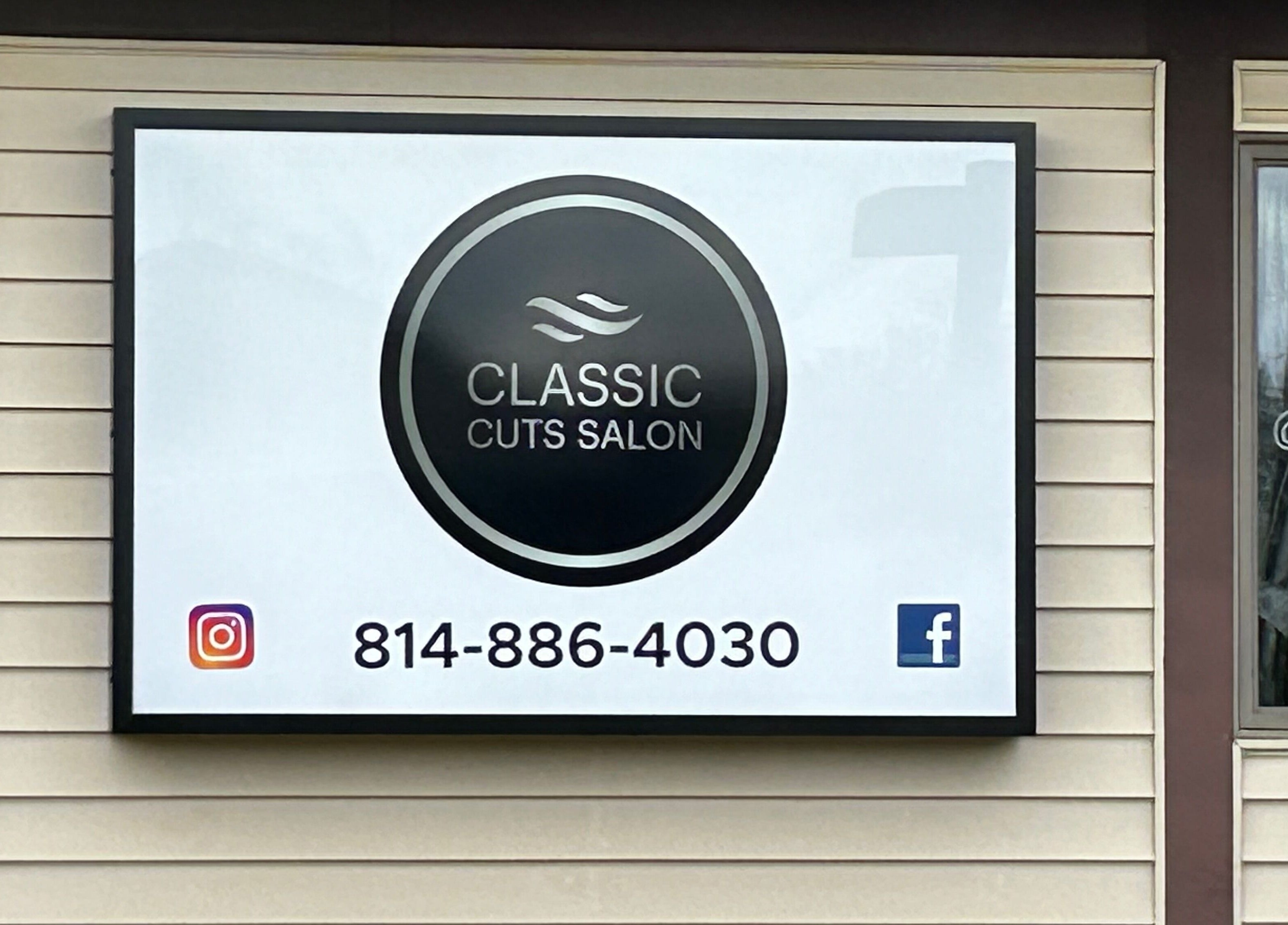Classic Cuts Salon signboard in Cresson, Pennsylvania, US, displaying contact details and social media logos.
