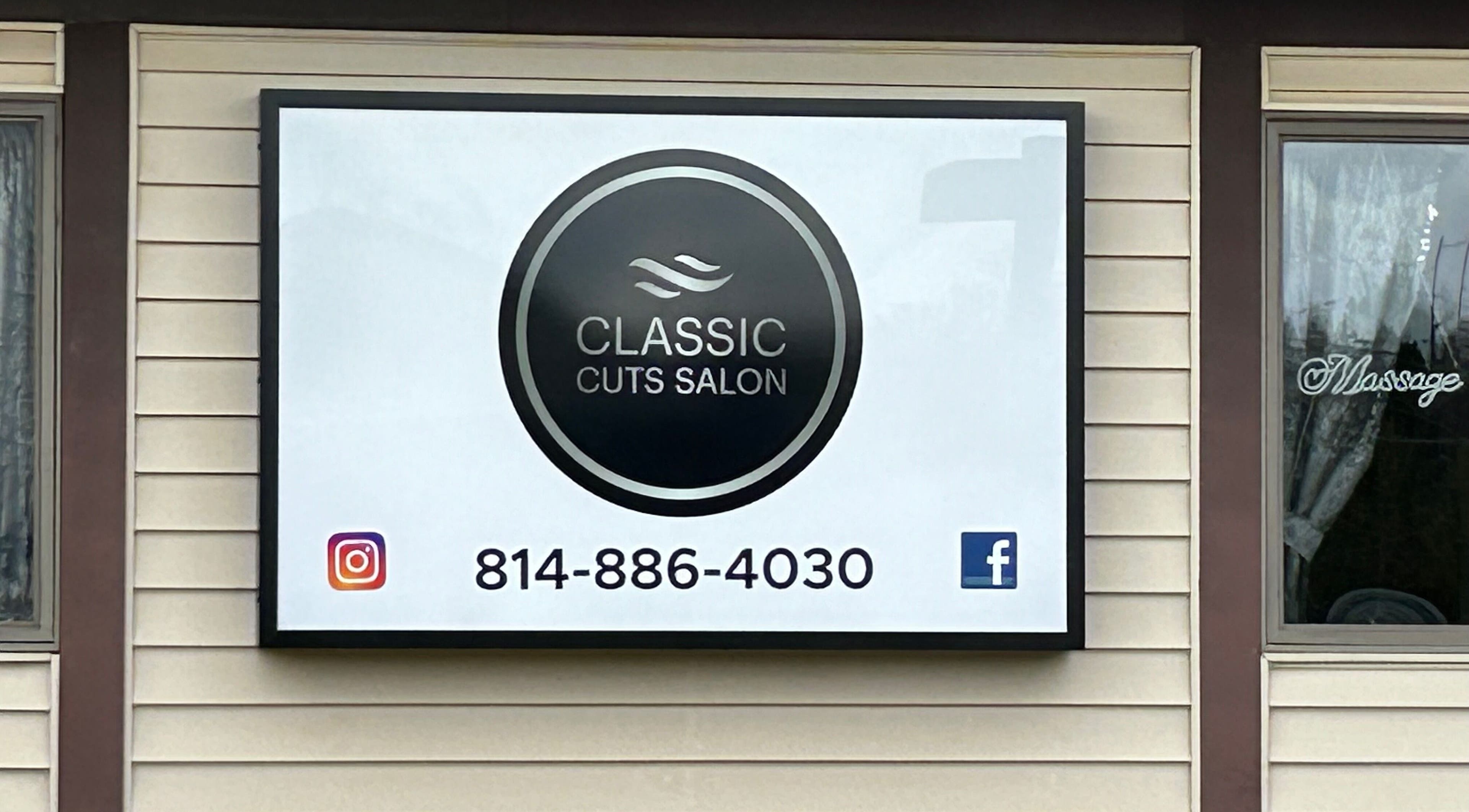 Classic Cuts Salon signboard in Cresson, Pennsylvania, US, displaying contact details and social media logos.