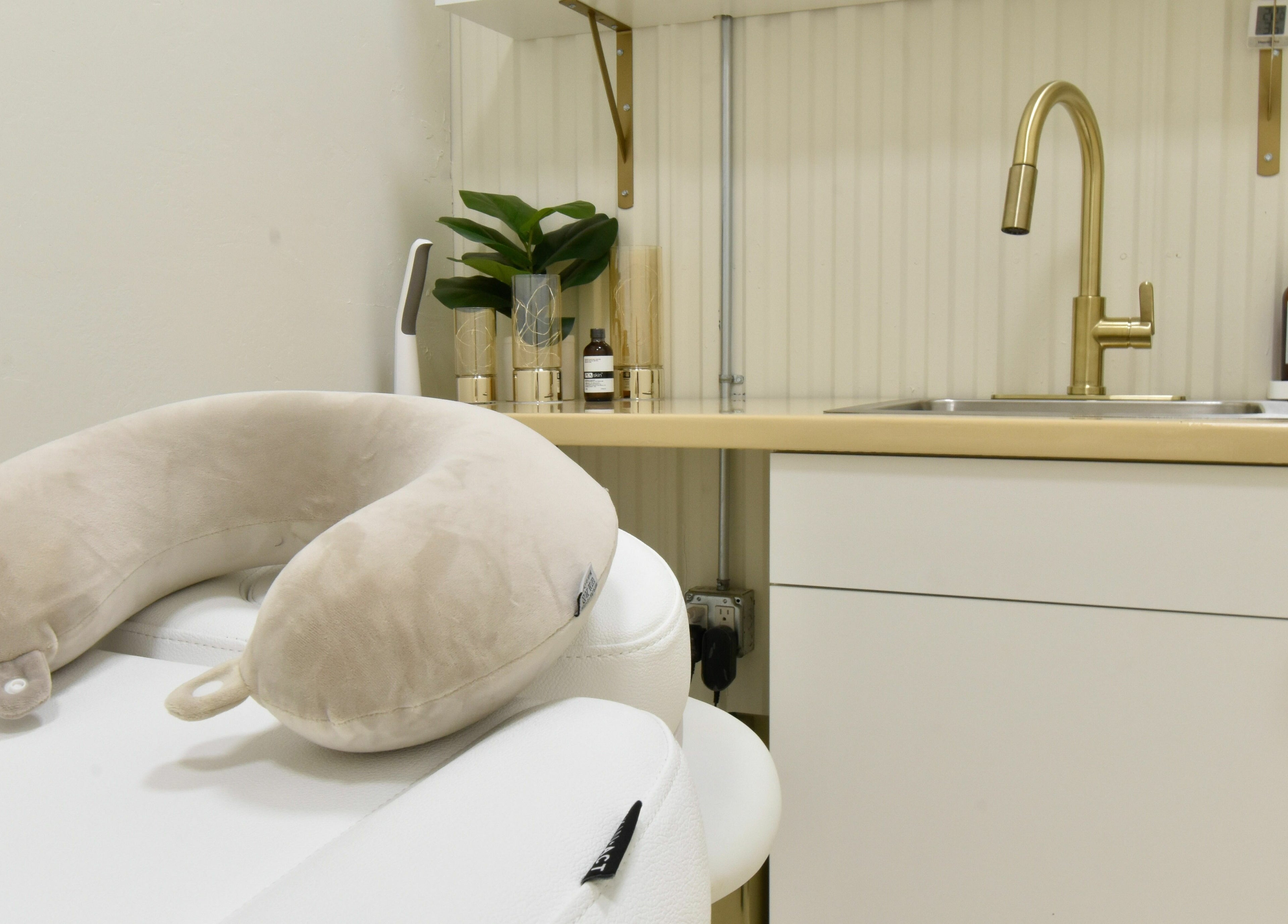 Relaxing spa room at Remedy Salon in Appleton, Wisconsin, US featuring plush neck pillow and modern sink area.
