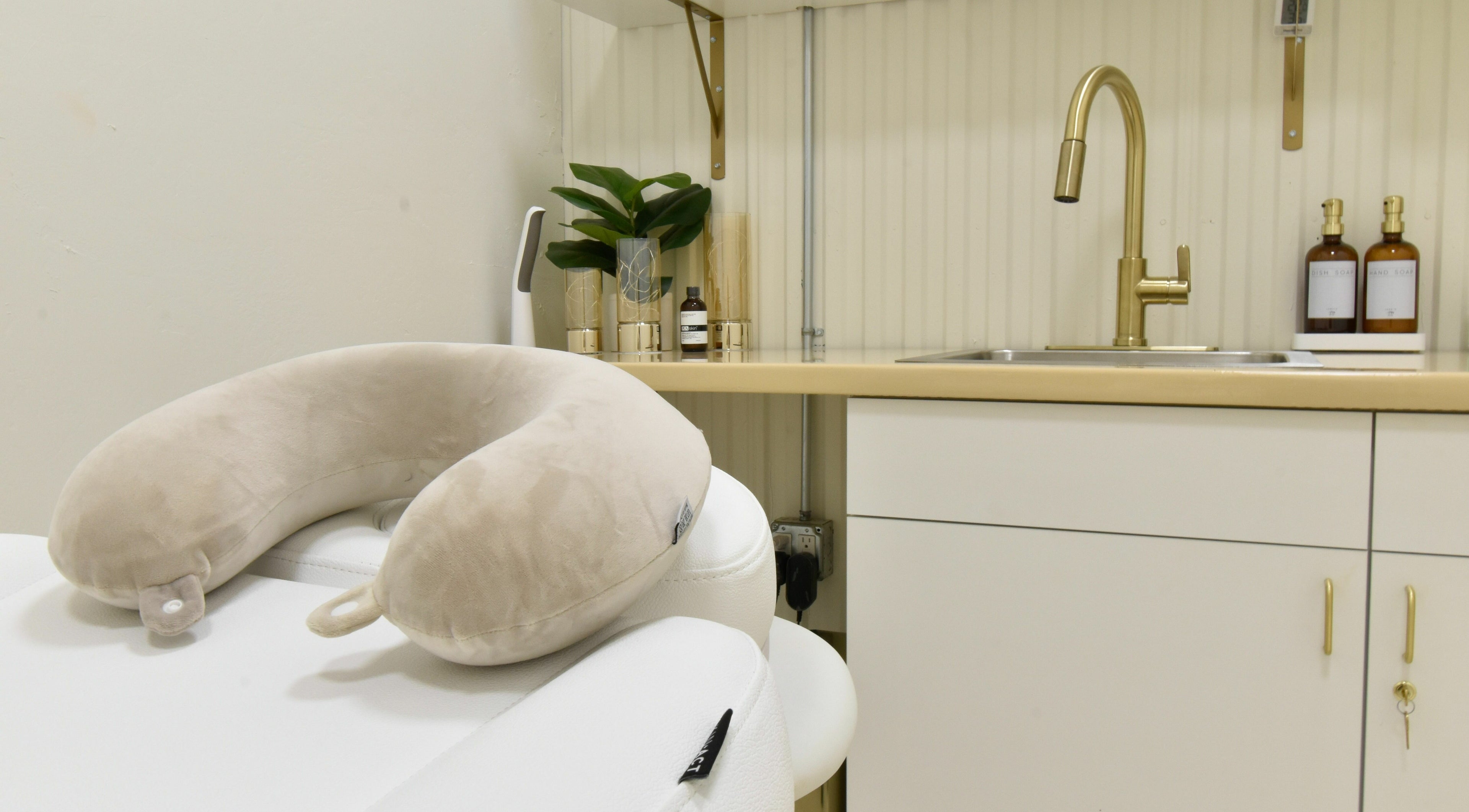 Relaxing spa room at Remedy Salon in Appleton, Wisconsin, US featuring plush neck pillow and modern sink area.