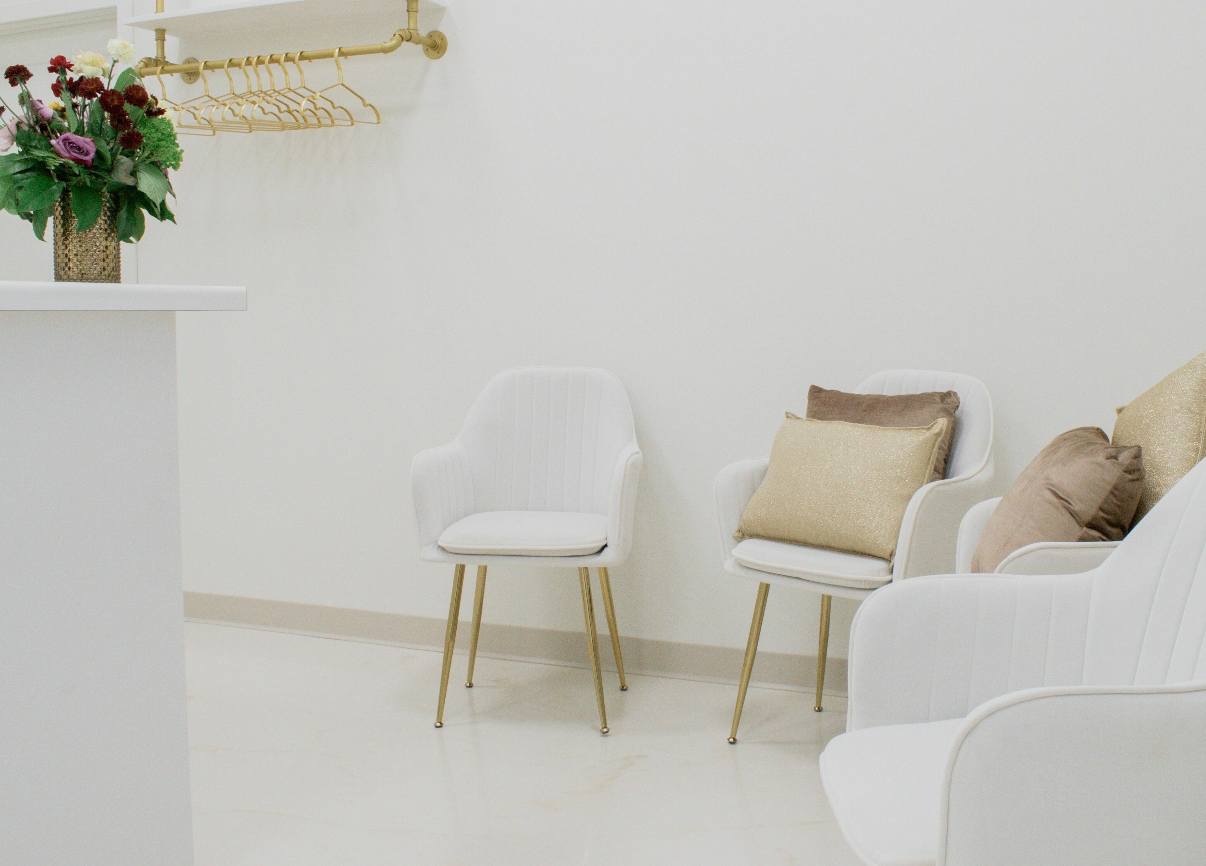 Sophisticated seating area in Remedy Salon, Appleton, Wisconsin, US, featuring chic white chairs and floral decor.