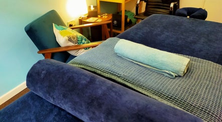 Relaxing therapy room at AmberLuna Apothecary, Bristol, England, GB, featuring a plush chair and cozy blankets.