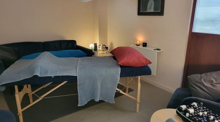 Cozy massage room at AmberLuna Apothecary in Bristol, England, GB, with soft lighting and a plush massage table.