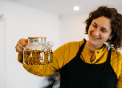 Person holding a herbal tea glass at AmberLuna Apothecary, Bristol, England, GB, showcasing natural wellness.
