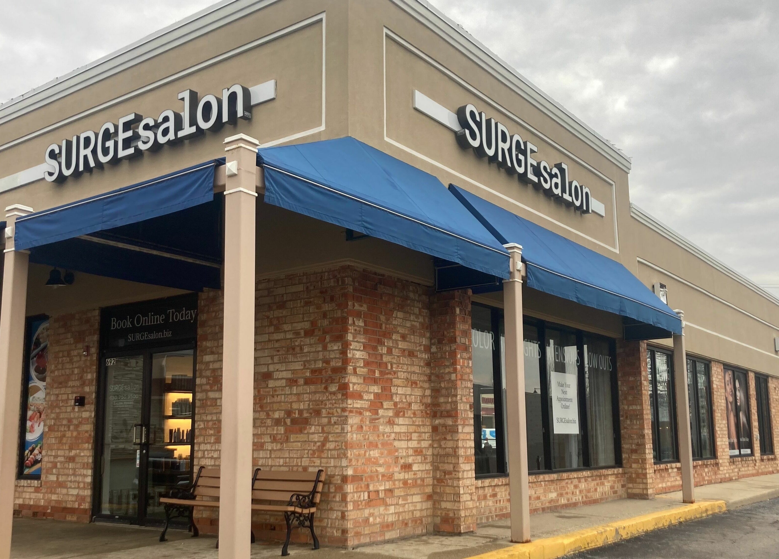Exterior view of Surge Salon in Glen Ellyn, Illinois, US with a blue awning and inviting entrance.