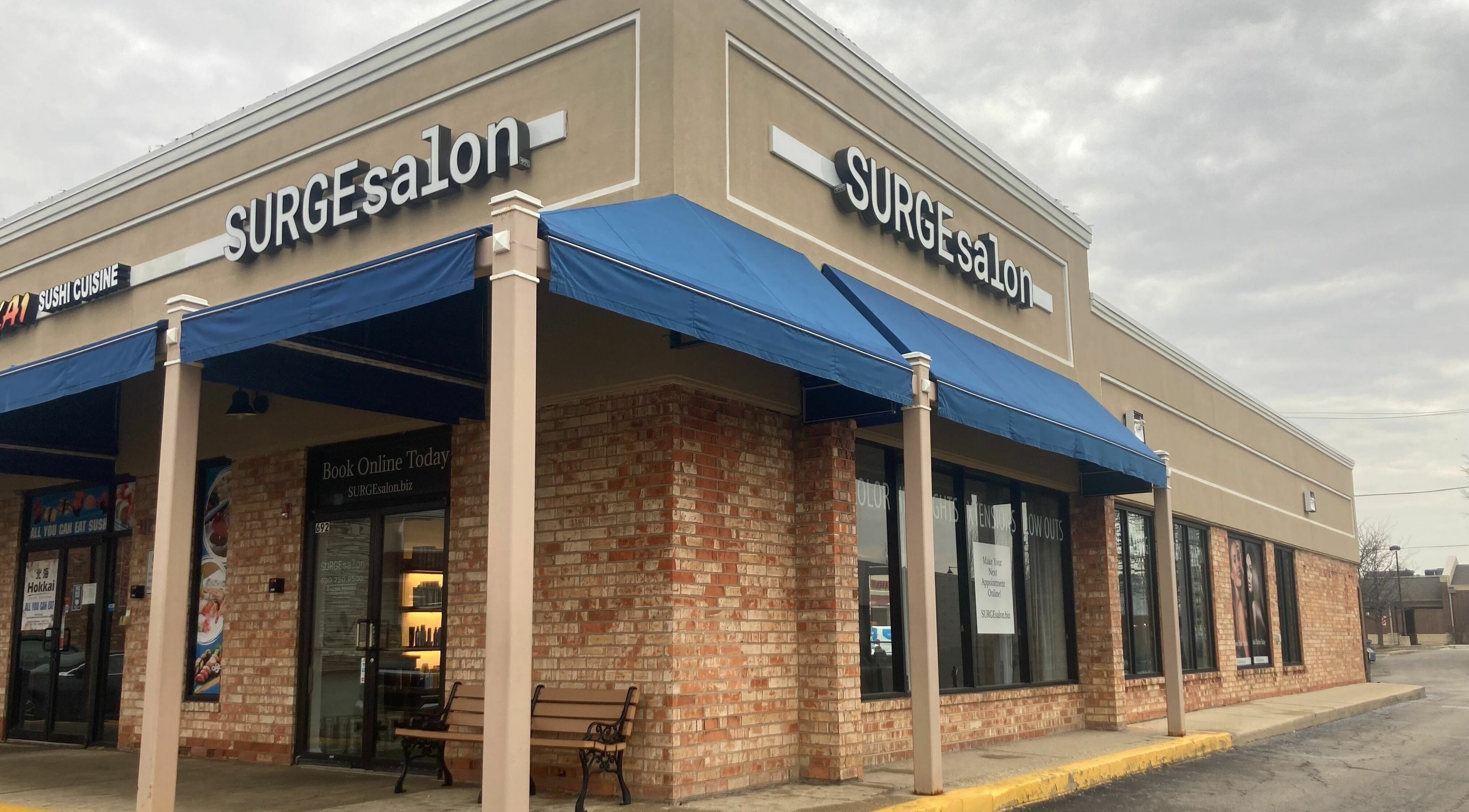 Exterior view of Surge Salon in Glen Ellyn, Illinois, US with a blue awning and inviting entrance.