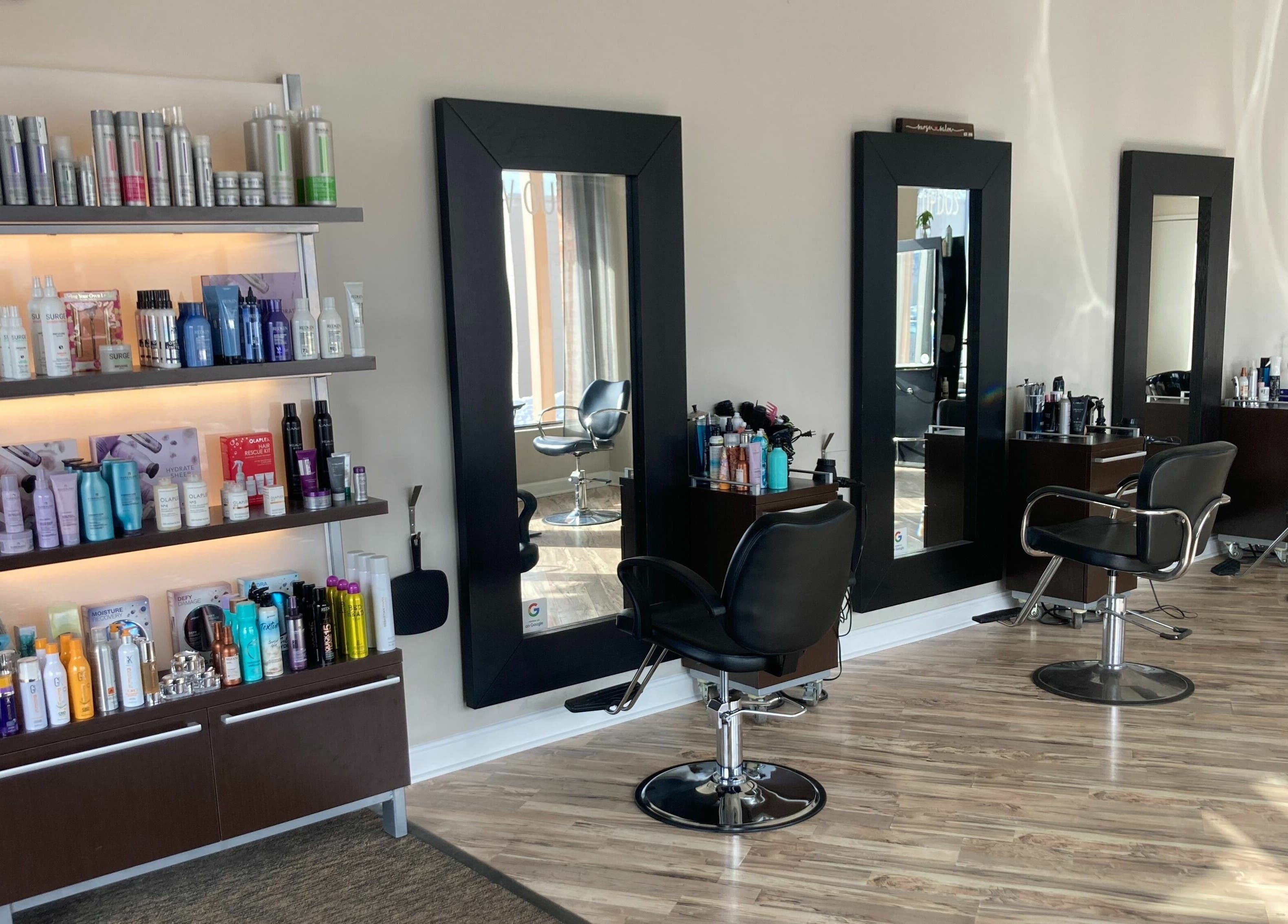 Modern hair salon interior with styling mirrors at Surge Salon, Glen Ellyn, Illinois, US. Professional products displayed.