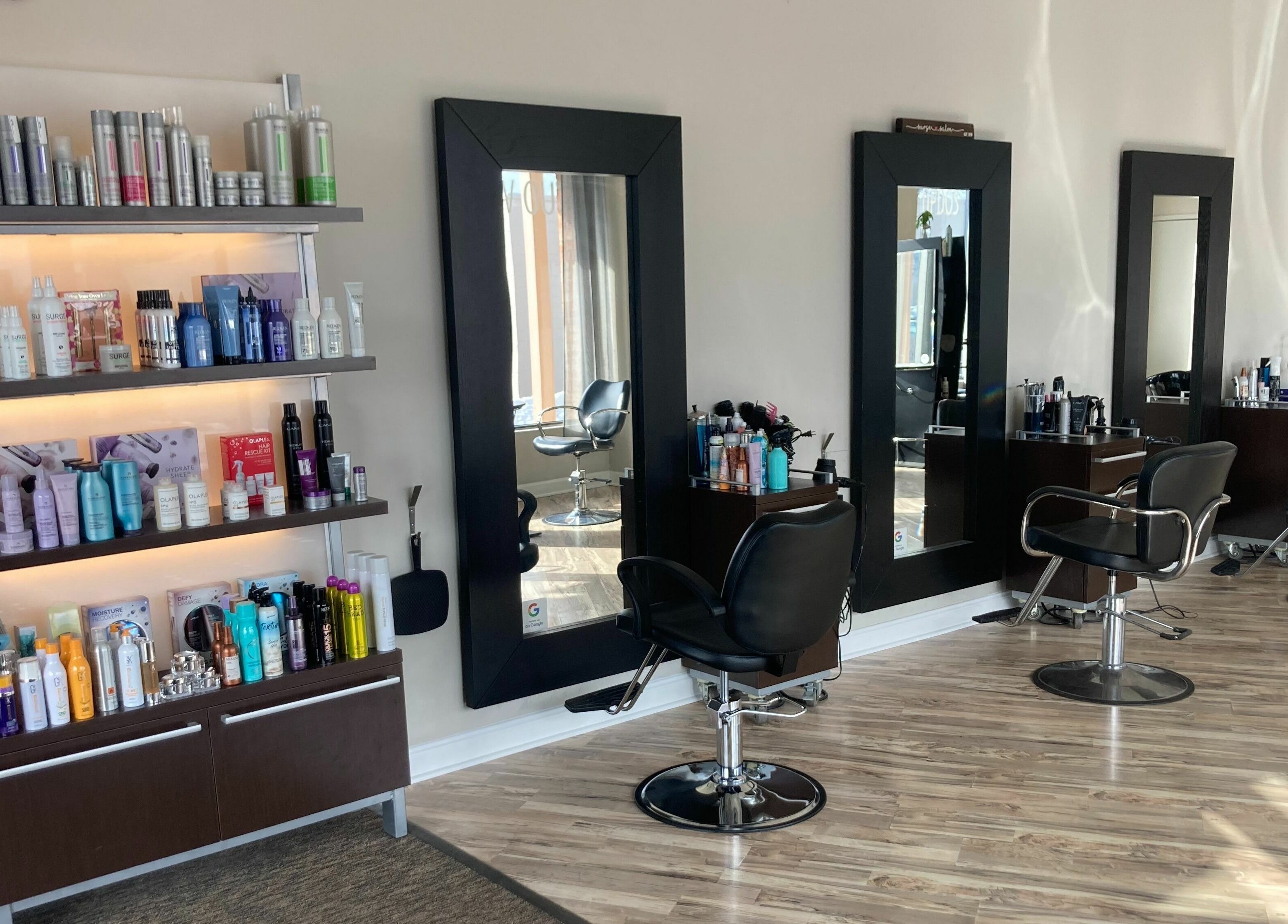 Modern hair salon interior with styling mirrors at Surge Salon, Glen Ellyn, Illinois, US. Professional products displayed.