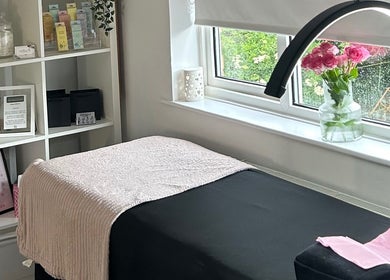 Calming treatment room at Beautology Newcastle, Whitley Bay, England, GB with a bed, flowers, and shelves.