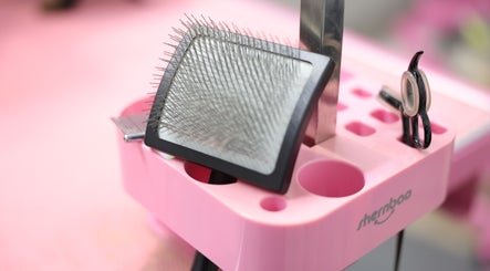 Pet grooming tools at Cuts For Pups, Melbourne, Victoria, AU. Includes a brush and scissors on a pink stand.