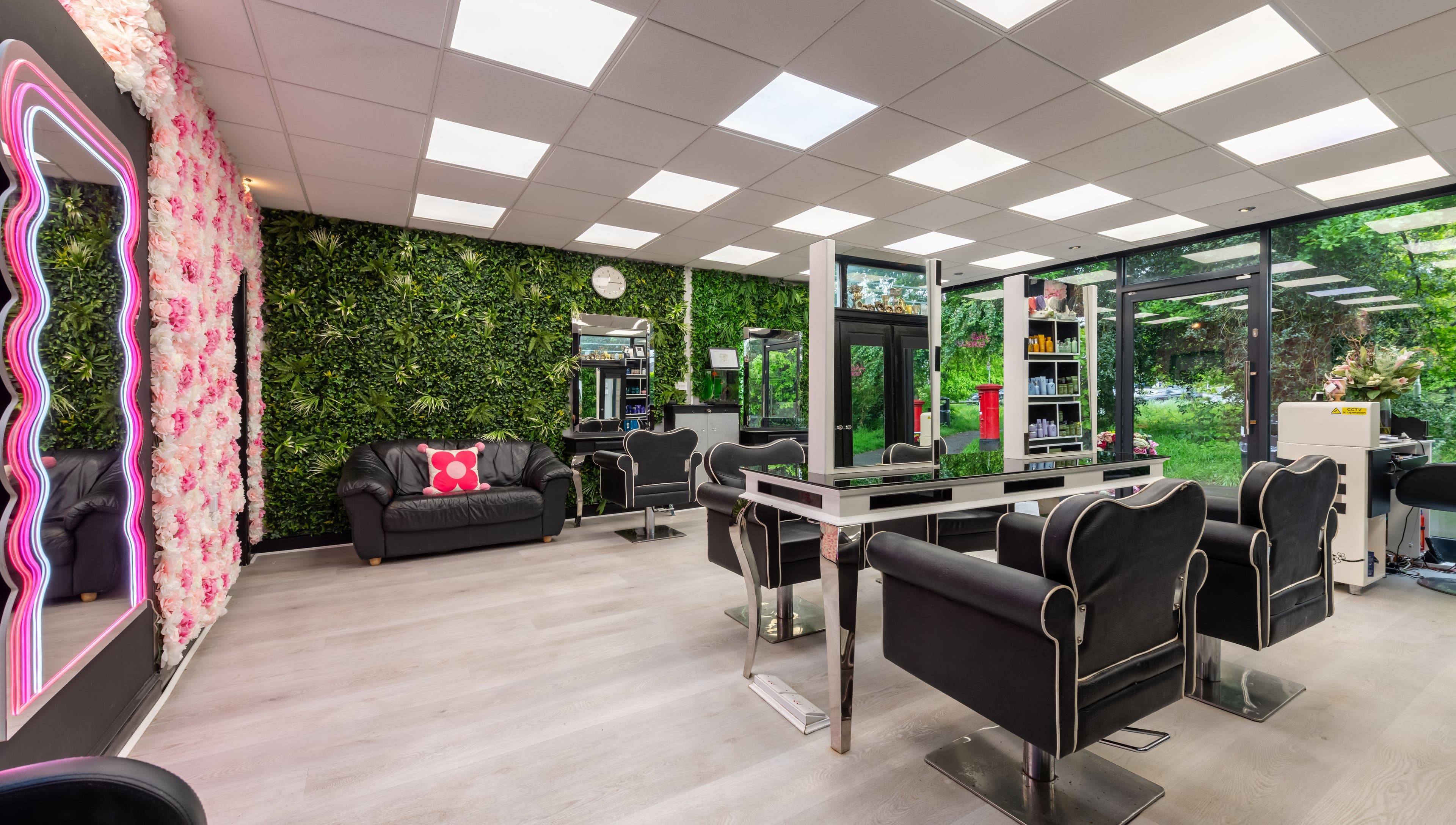 Stylish interior of Chop and Change salon in Addlestone, England, GB featuring lush greenery and modern seating.