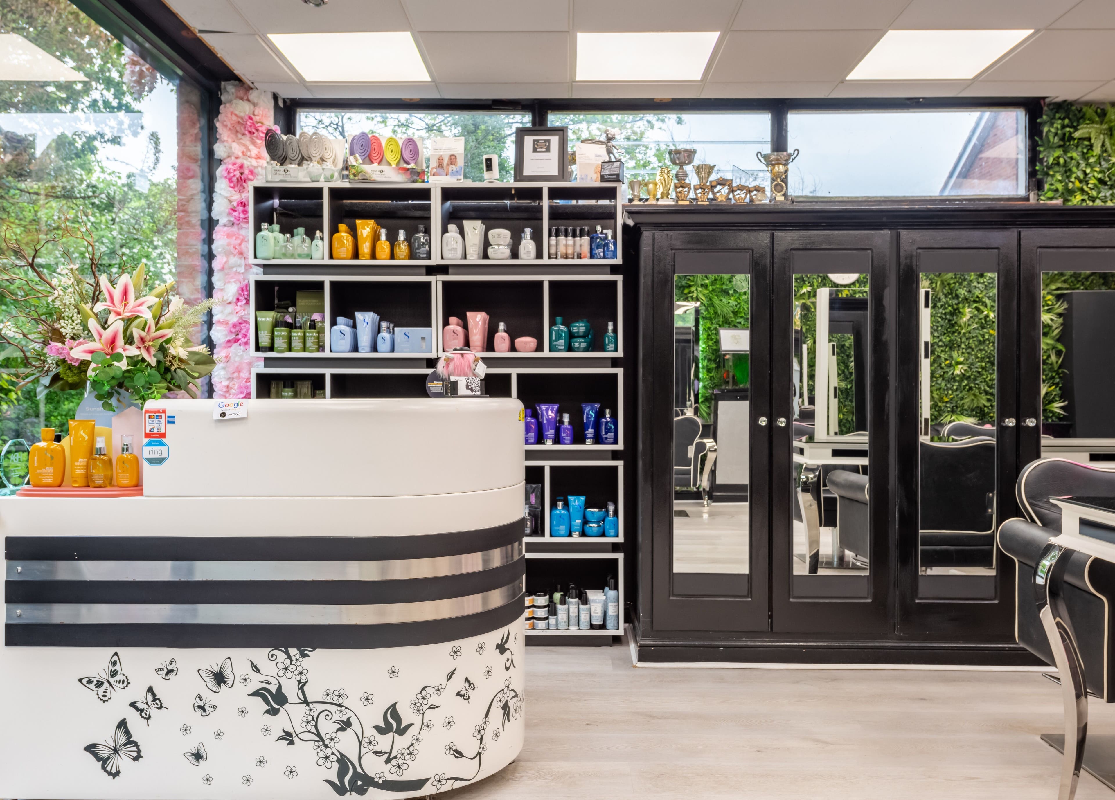 Reception area of Chop and Change in Addlestone, England, GB with stylish decor and beauty products on display.