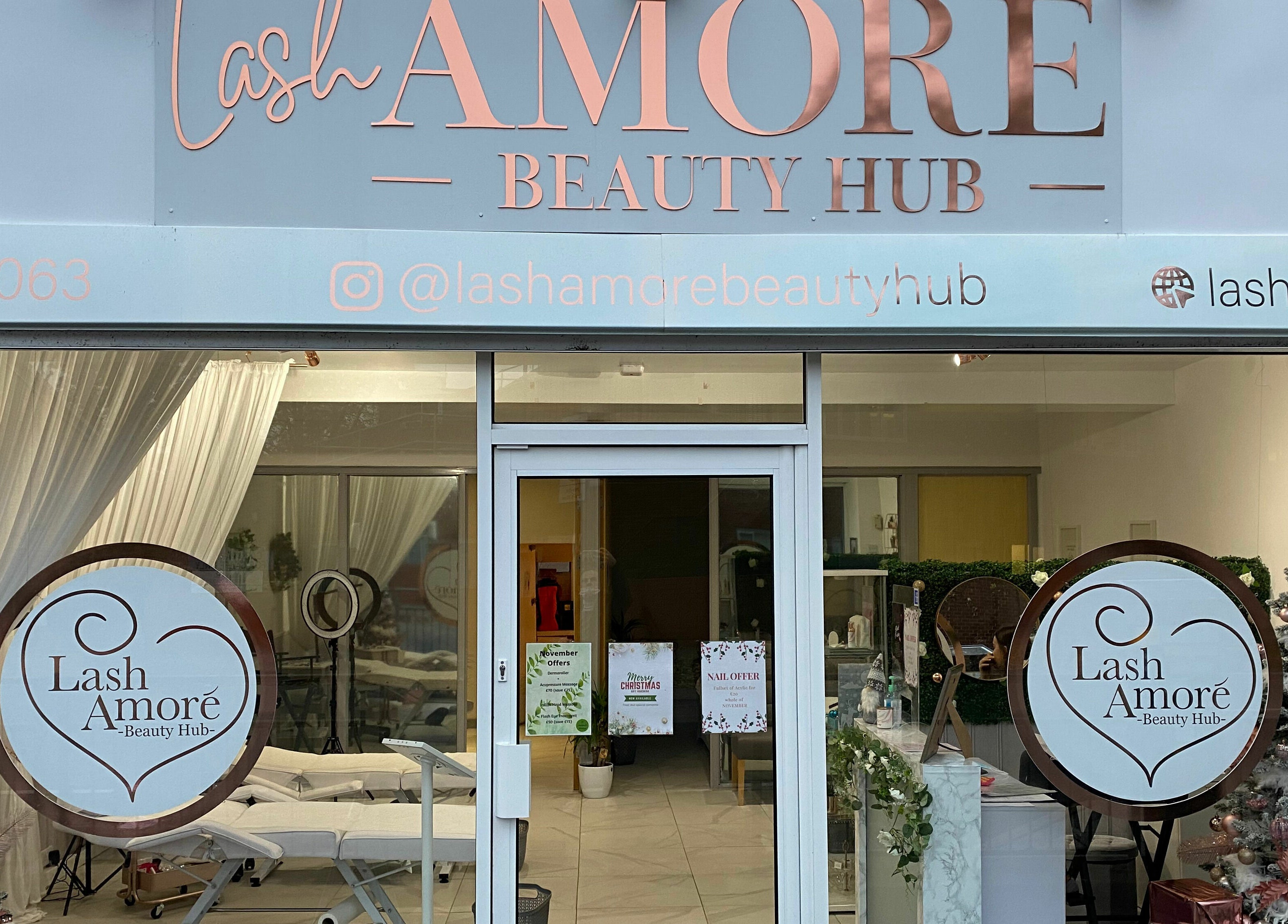 Front entrance of Lash Amoré Beauty Hub in West Drayton, England, showcasing festive decor and signage.