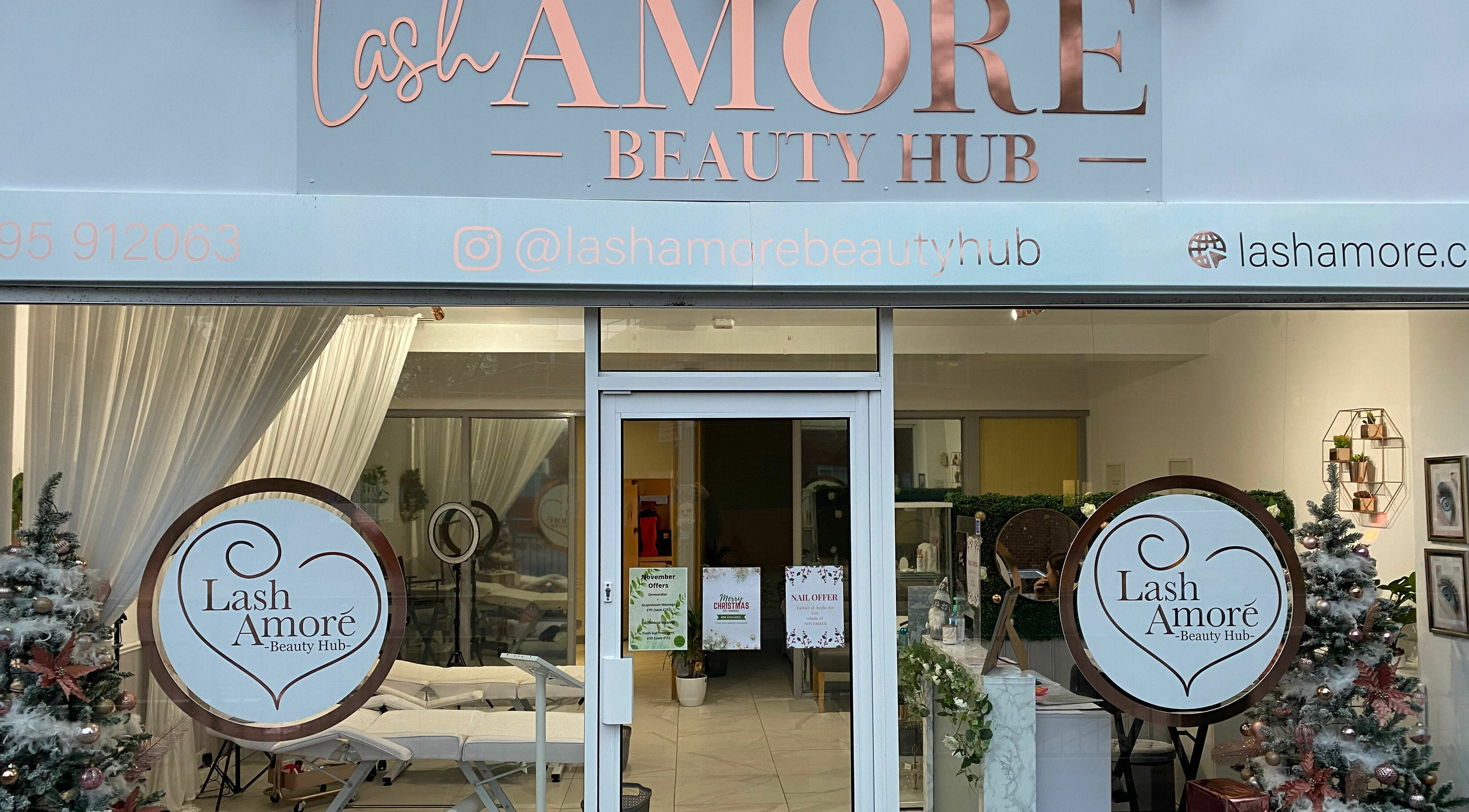 Front entrance of Lash Amoré Beauty Hub in West Drayton, England, showcasing festive decor and signage.