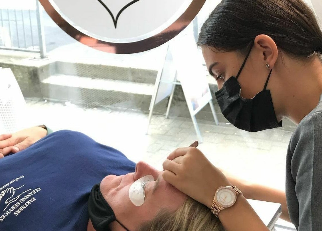 Lash artist applying extensions at Lash Amoré Beauty Hub, West Drayton, England, GB, enhancing client's lashes.