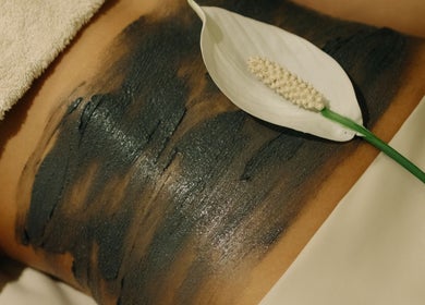 Luxurious mud body wrap at Wellness Club @ Vilalara Grand Hotel in Lagoa, Faro, PT with a white flower accent.