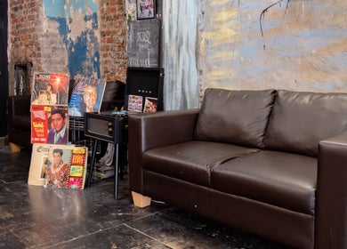 Stylish retro lounge at Unparalleled 145, London, England, GB with vintage record decor and leather sofa.