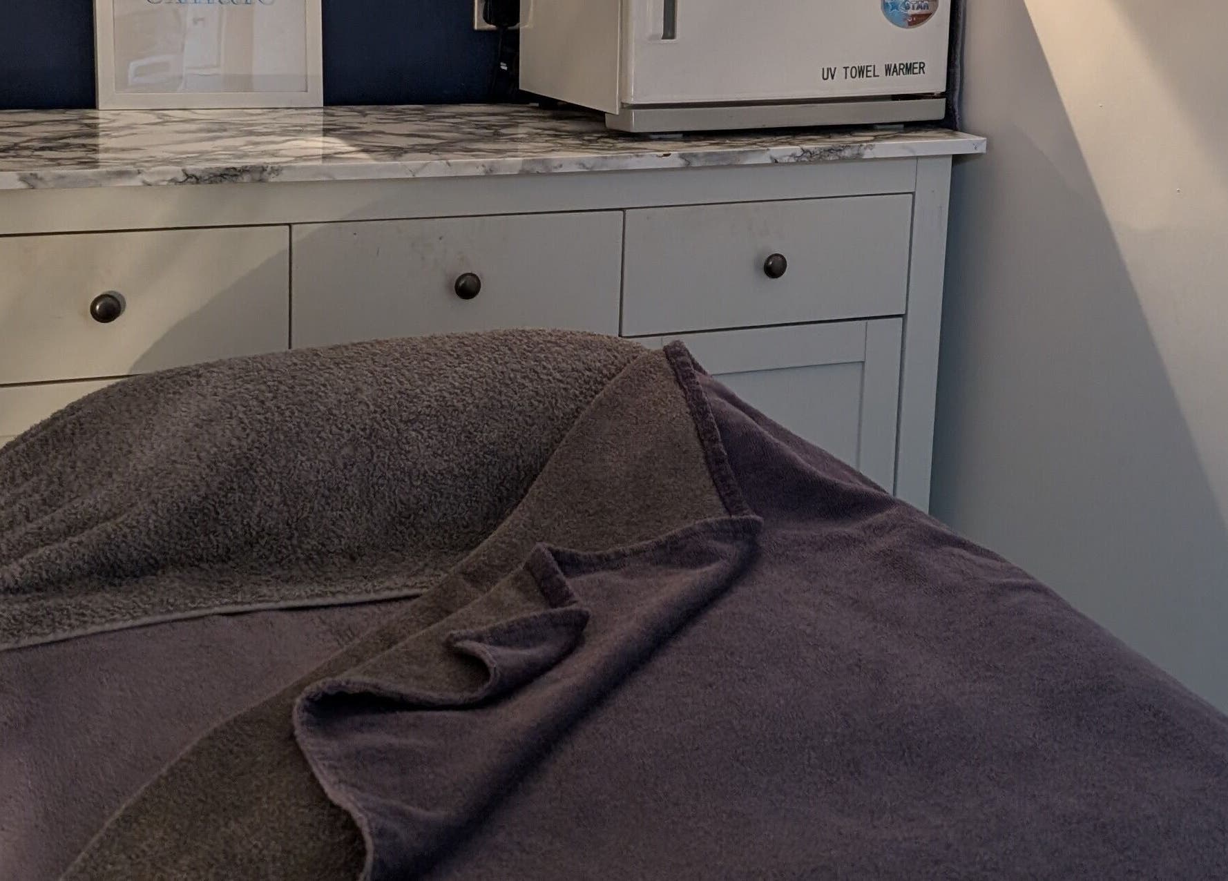 Relaxing treatment room at Sensational Beauty in Mirfield, England, GB with cozy towels and cabinetry.
