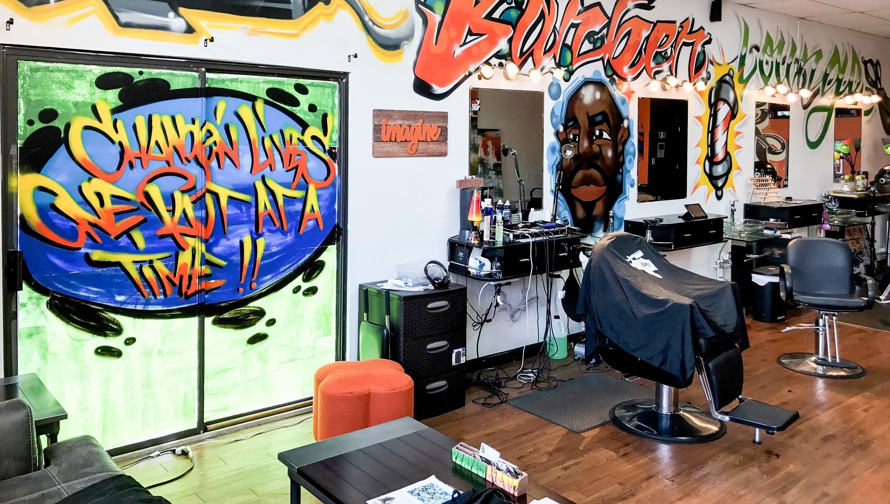 Inside Perfect Blendz Barber Lounge, Jonesboro, Georgia, with vibrant graffiti art and modern barber chairs.