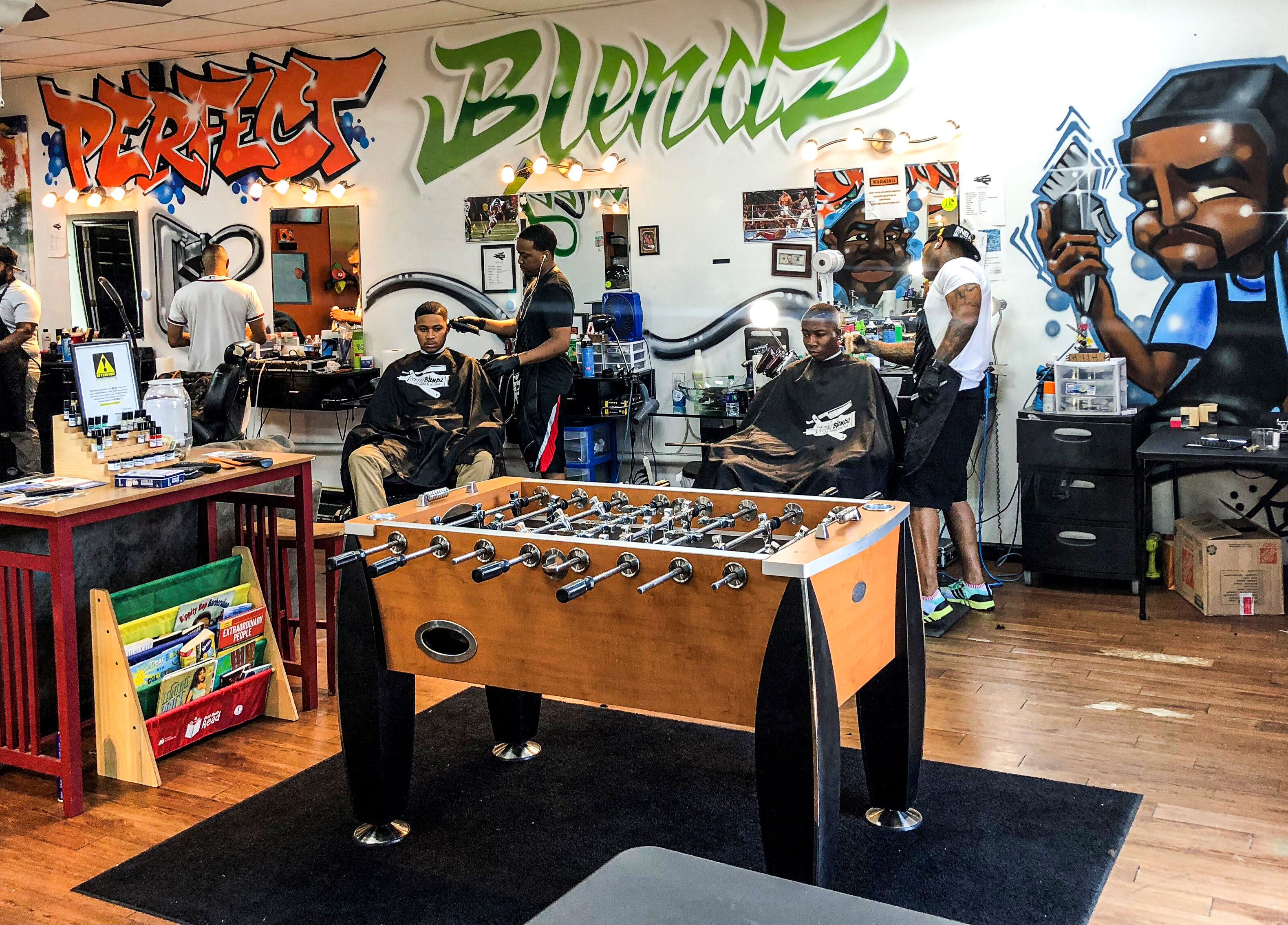 Interior of Perfect Blendz Barber Lounge in Jonesboro, Georgia, US with vibrant murals and foosball table.