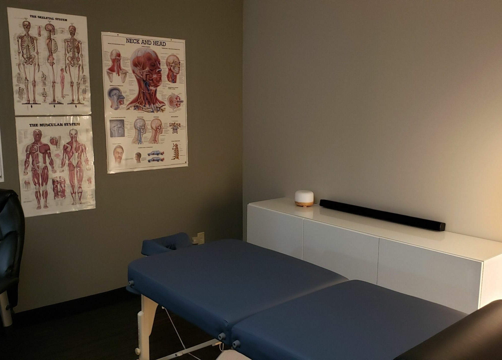 Therapy room at Piotr Gorecki Manual Therapy Clinic Inc., Calgary, Alberta, CA with anatomical charts and massage table.