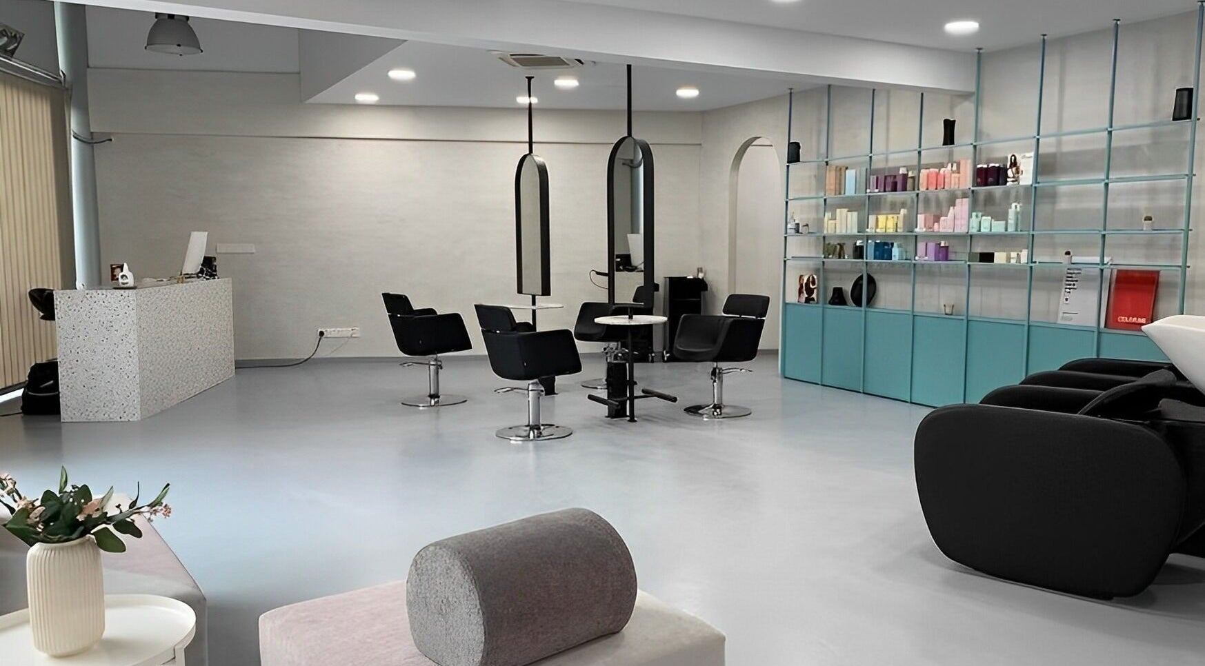 Modern interior of Alchemy Hair Salon in Nicosia, Nicosia, CY with stylish black chairs and elegant product shelves.