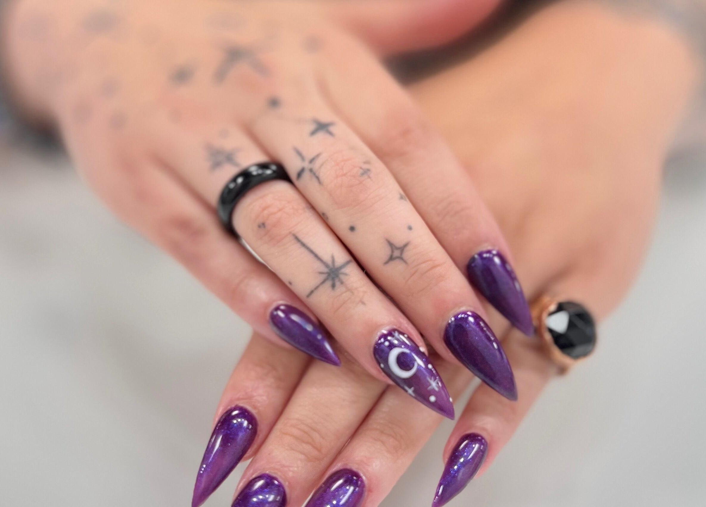 Intricate purple nail art at Eversaint Salon, New Orleans, Louisiana, US, featuring moon and star designs.